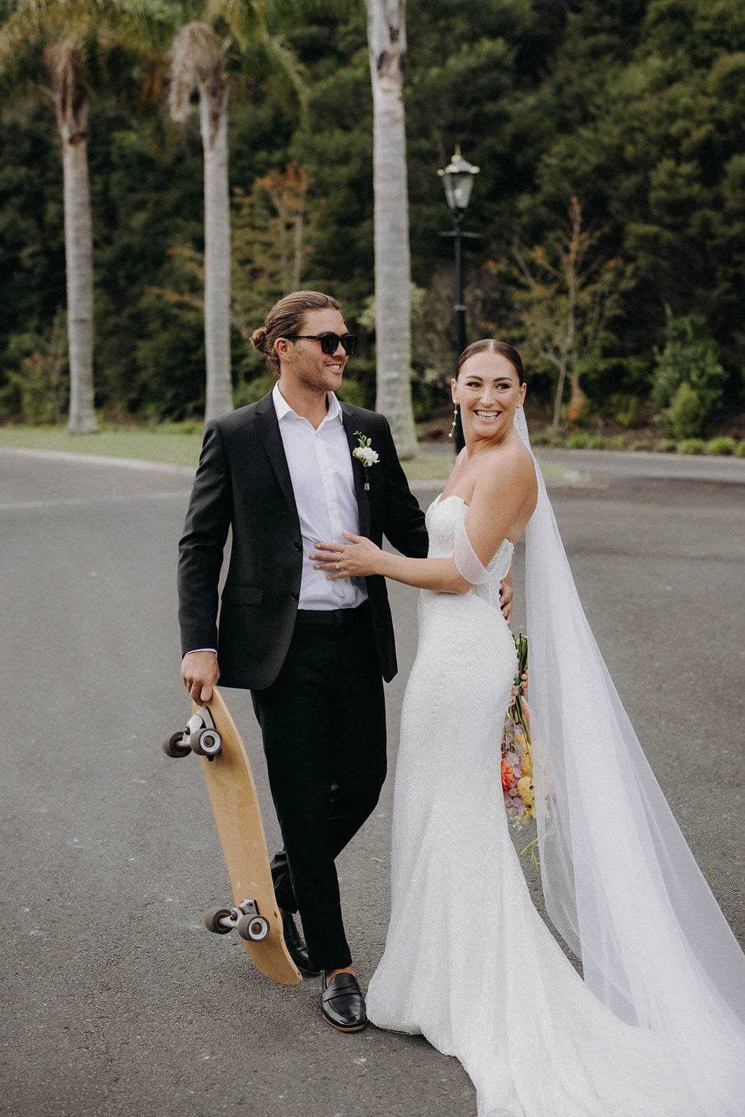 Bride Leah walks along the New Zealand coast wearing IMOGEN pearl drop earrings and a cathedral-length wedding veil from Amélie George Bridal, paired with an off-the-shoulder sequin gown by Trish Peng.