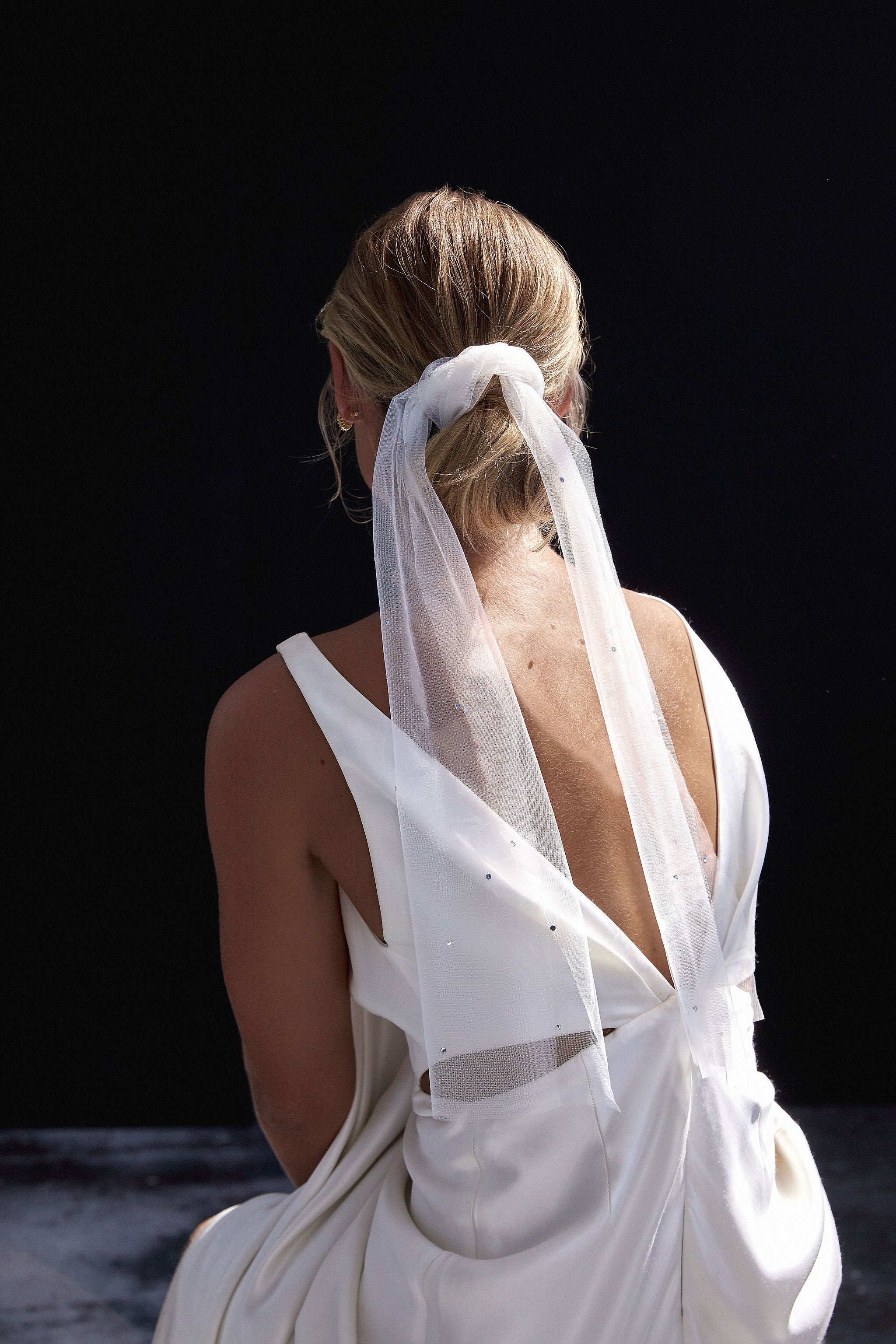 Bride showcasing a sophisticated bridal veil tie, adding romantic charm to her wedding hair.