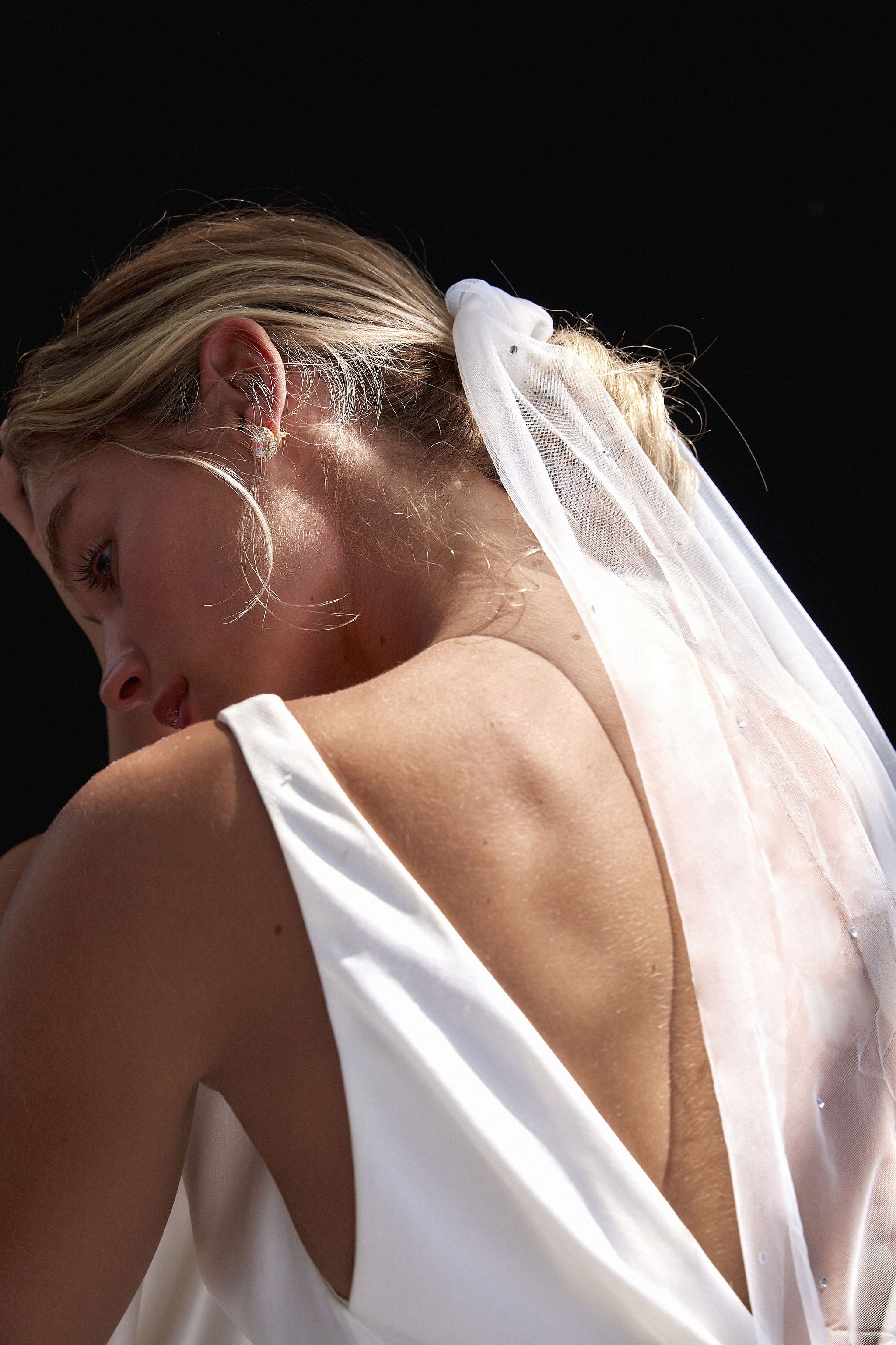 Bride wearing a tulle wedding veil tie around her hairstyle for a minimalist bridal look.