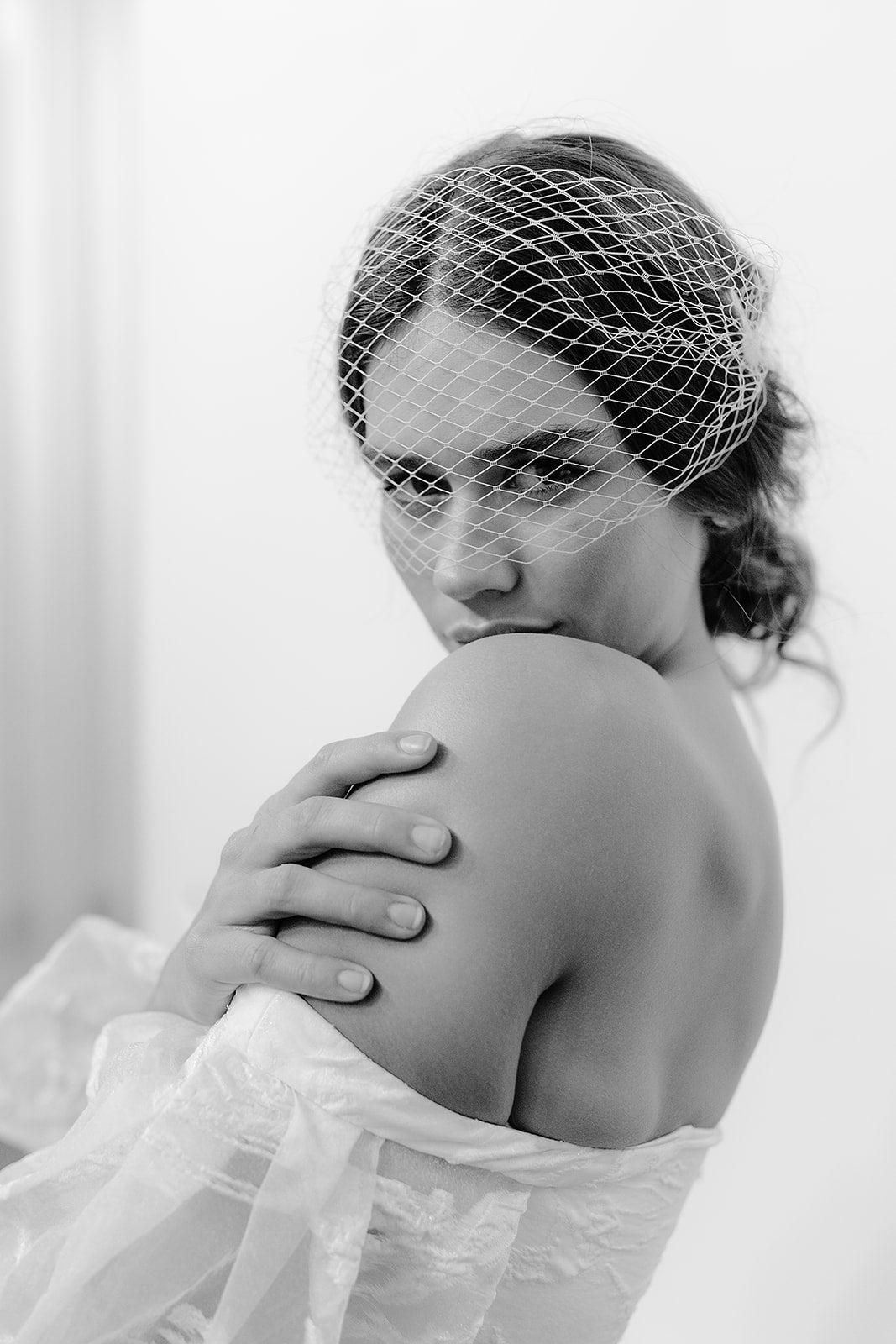 Beautiful bride wearing a short French net birdcage veil, adding a vintage touch to her wedding dress for a modern yet classic bridal style.