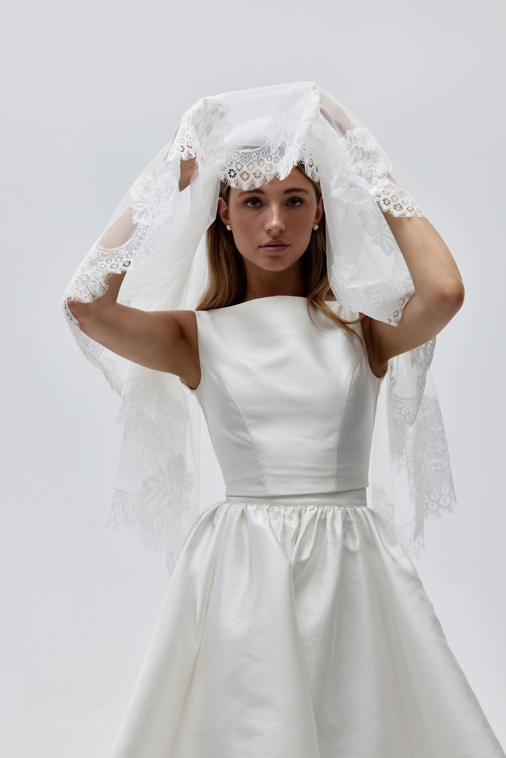 Close-up of bride wearing a lace wedding veil with blusher, highlighting the delicate lace edging and soft fabric.