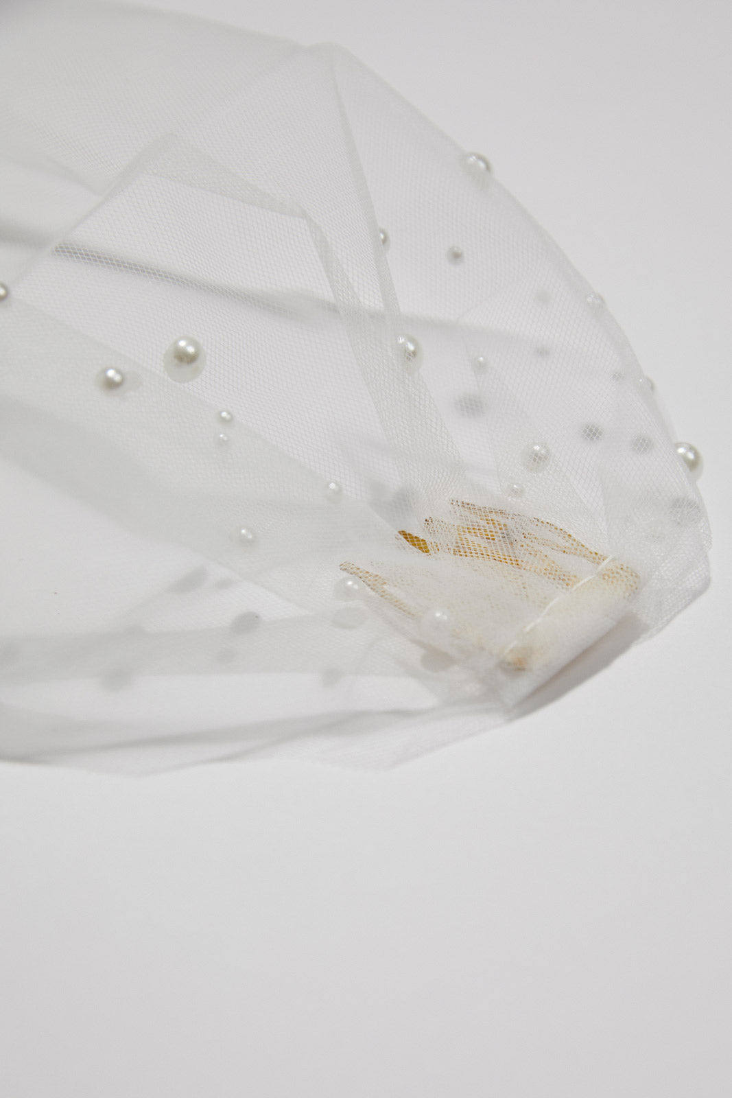 Flatlay of the Pearl Birdcage Wedding Veil, showcasing its delicate pearls and elegant design as a timeless bridal accessory.