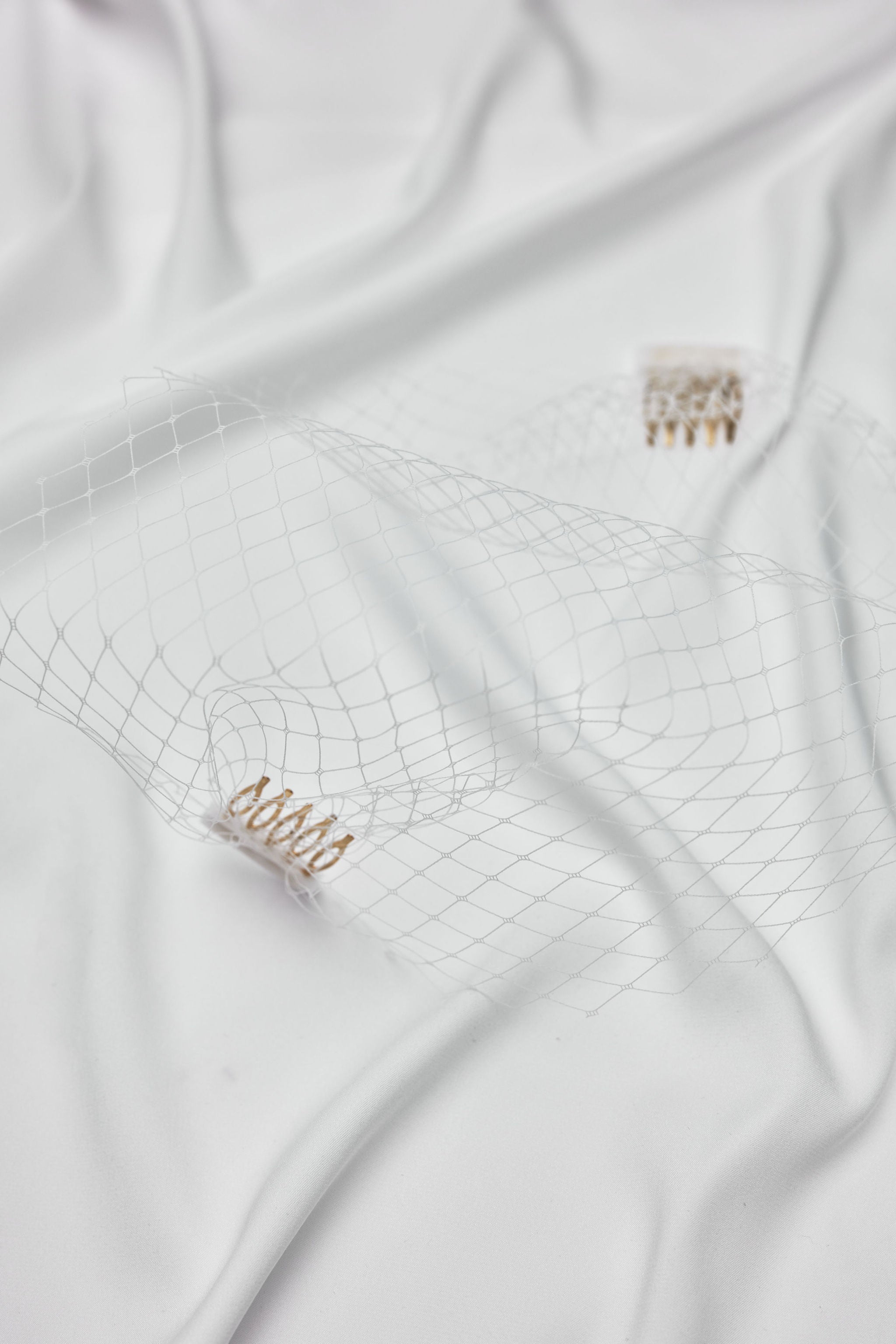 Flatlay of a bridal net birdcage veil, combining vintage charm and modern sophistication, perfect for brides seeking a unique wedding accessory.