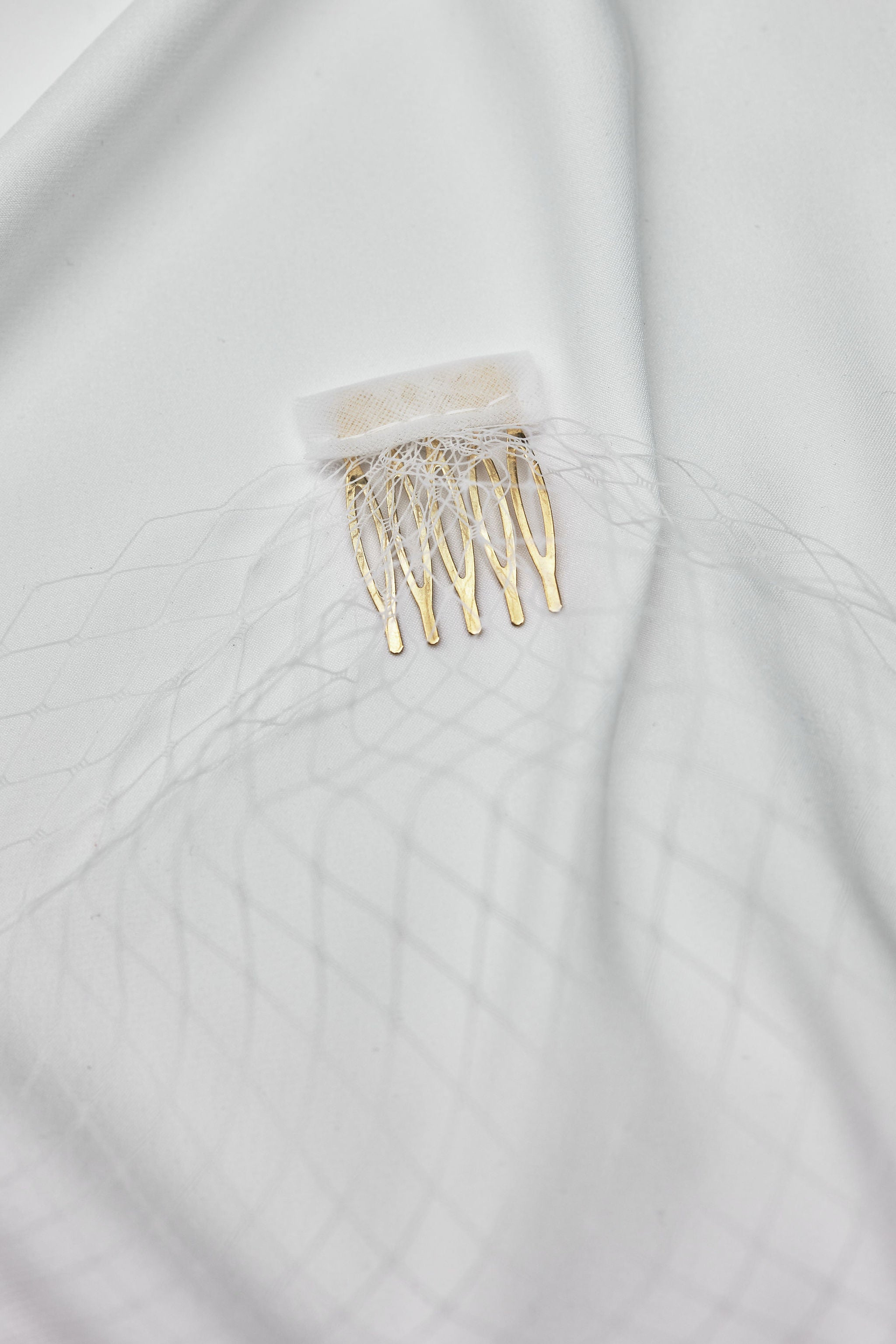 Close-up flatlay of a delicate net birdcage veil, a timeless bridal accessory perfect for adding elegance to any wedding look.
