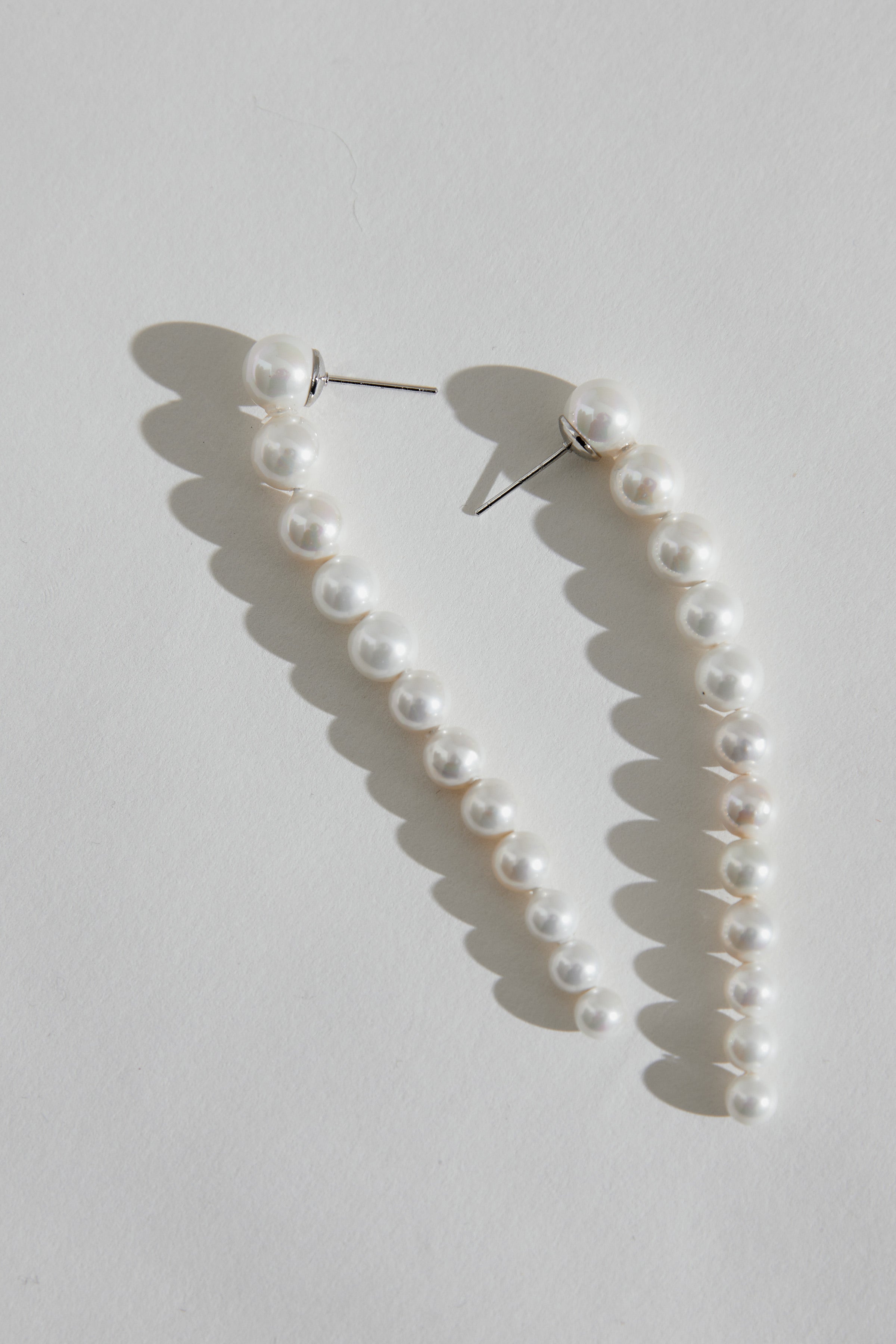 OLYMPIA silver pearl drop earrings, a modern bridal accessory with smooth silver and elegant pearls, perfect for brides seeking understated beauty.