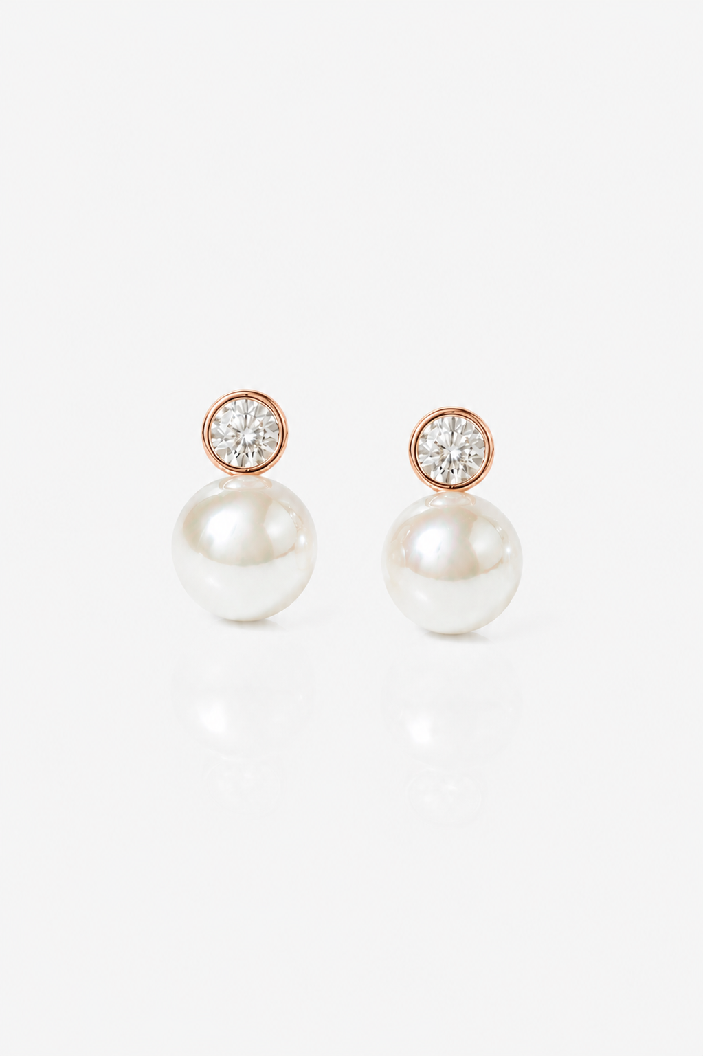 Minimalist Rose Gold Pearl Wedding Earrings with Crystal Accent on a white table in the sun - Elegant Bridal Jewelry for Timeless Beauty and Grace