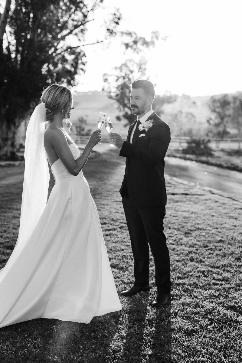Real bride wearing a short wedding veil and having champagne in the Australian country with her groom.
