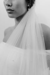 Radiant black & white brunette bride adorned in a stunning pearl wedding veil, with matching pearl chain earrings, adding a touch of timeless elegance to her strapless bridal gown