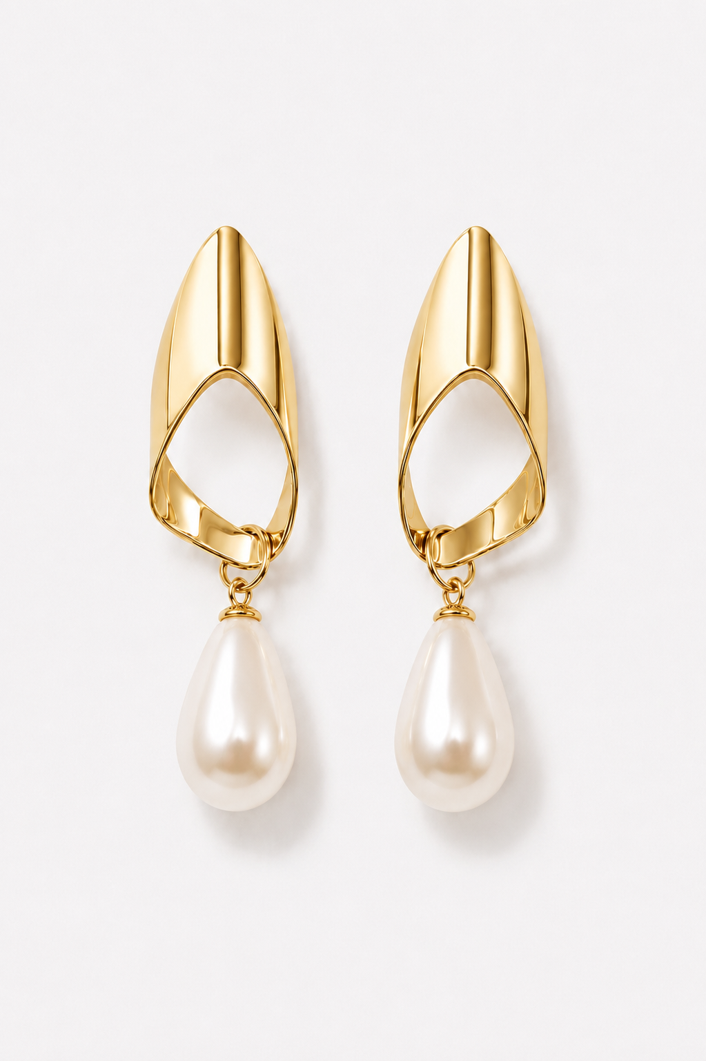 Gold earrings with pearl drops on a light background