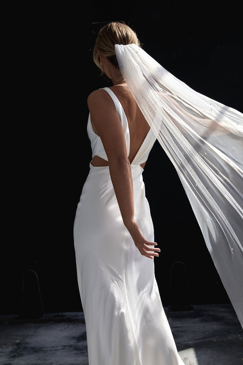long bridal pearl veil from behind showing comb attachment worn by a bride in a backless dress
