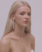 Video of a blonde bride with straight hair in a middle part showing her earrings which are pearl freshwater wedding drop earrings.