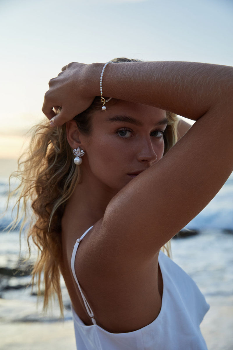 Harper floating pearl earrings worn on a modern bride on the beach with a matching pearl bracelet.