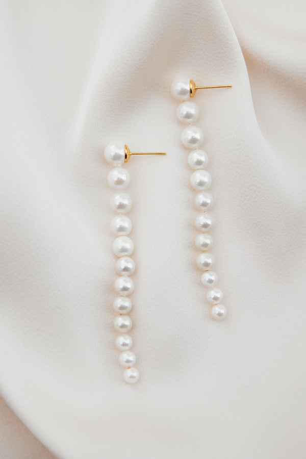 Exquisite Pearl handmade Chain Bridal Earrings with freshwater pearls from large to small which drops at the shoulders. Shown in image in a flatlay on ivory silk.