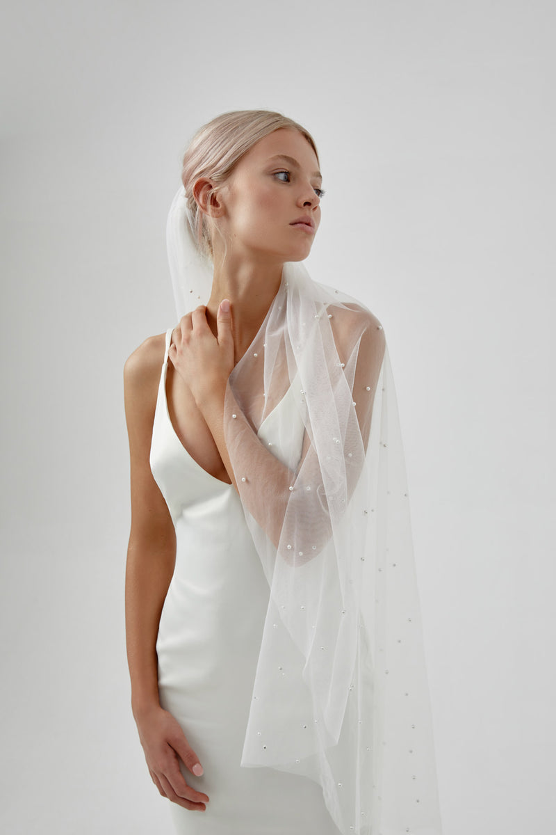 Pearl Bridal Veil, by Amelie George Bridal on a bride with her arm over her shoulder looking to the side