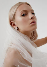 Long Wedding Veil with pearls draped over a bride's shoulder as she looks to the camera wearing a sparkling statement earring