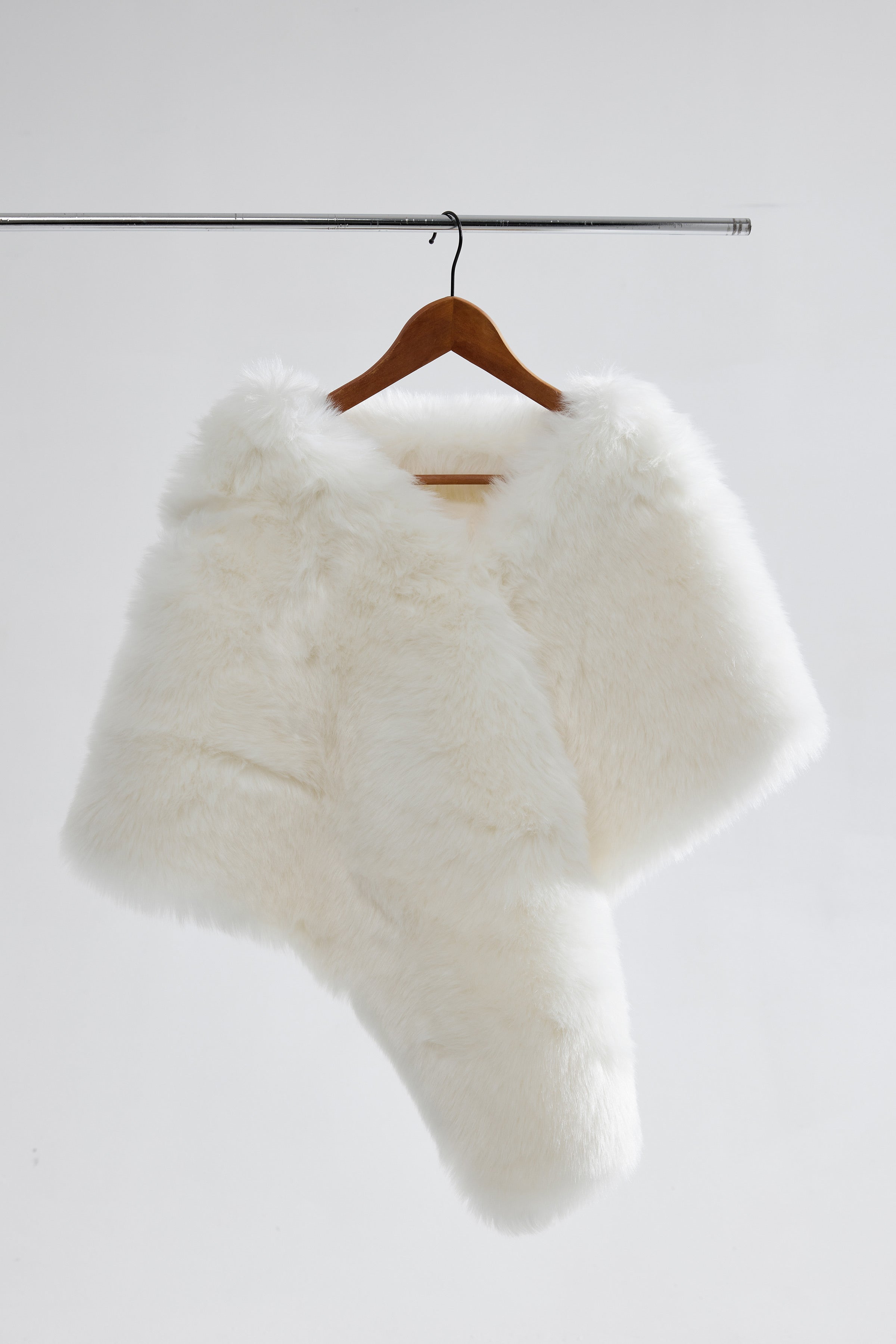 Flatlay of a vegan fur tiered wedding shawl displayed on a soft linen background